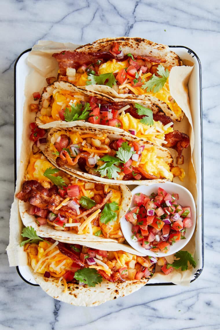 Breakfast Tacos - An absolute crowd favorite! Served in warm tortillas with crispy bacon, potatoes, scrambled eggs and your favorite toppings!